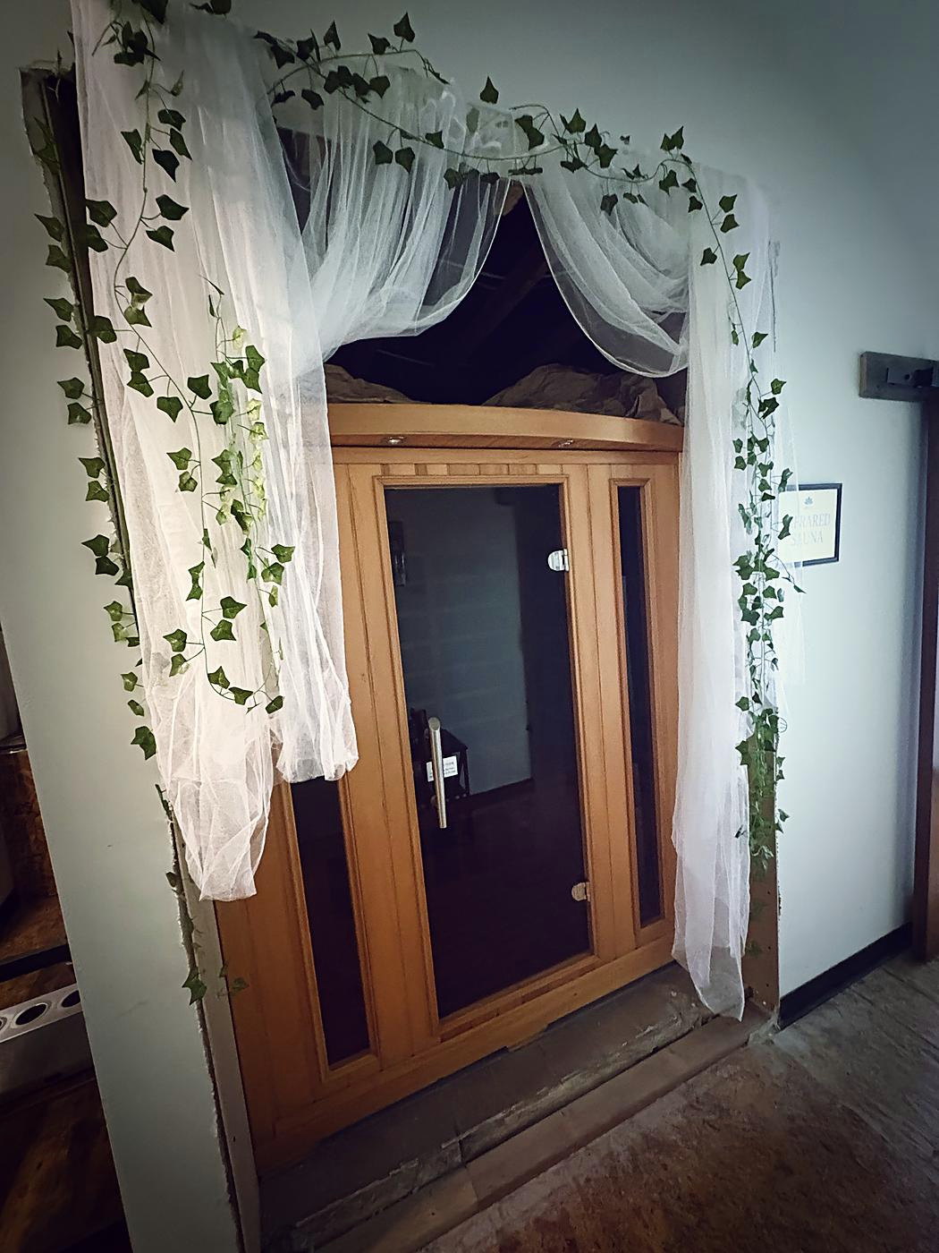 Sauna entrance framed with drapery and greenery
